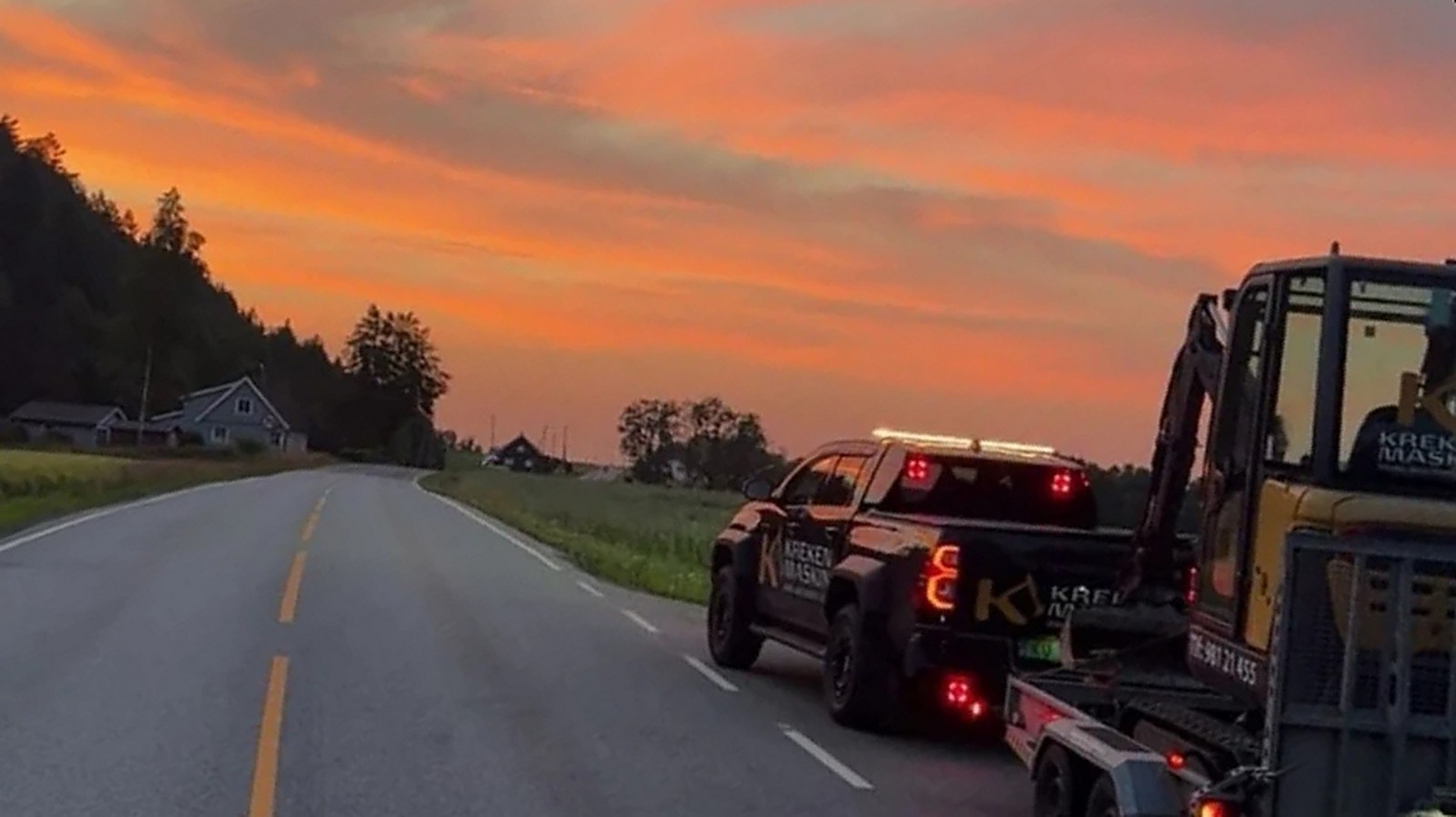 Kreken Maskin sin bil med gravemaskin på henger i solnedgang